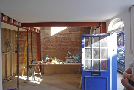 Internal construction site of listed building. Exposed brick walls, red steel joists, internal wooden walls.