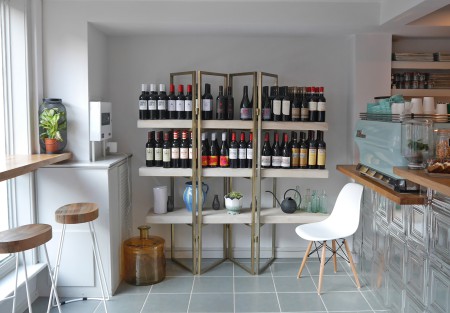 Shelving with a selection wine bottles. A serving counter with a coffee making machine.