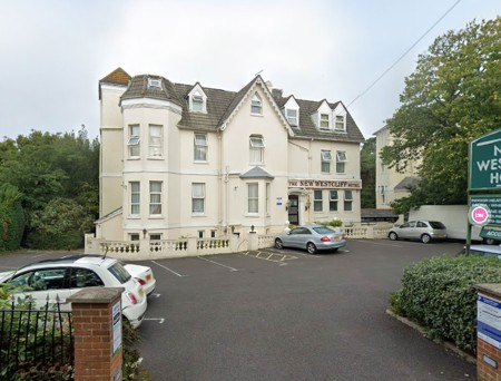 The New Westcliff hotel in Bouremouth. A white, three story, Victorian villa styled building.